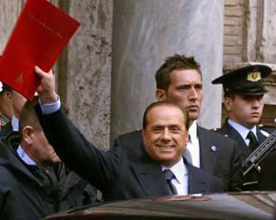 Italy's Prime Minister Silvio Berlusconi waves a red folder while leaving the Senate building in Rome April 20, 2005. Berlusconi moved to end the crisis that has threatened to tear his coalition apart by announcing he would resign on Wednesday and immediately form a new administration with the same allies. 