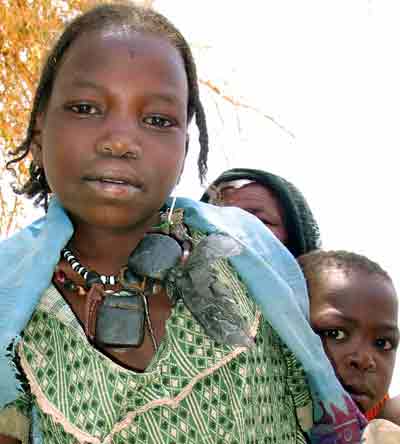 Sudanese girl adorned with 'hijab' talisman ornaments on her neck, worn by many tribes which they believe can save them from bad luck, poses as her sibling peeps from her back, at the Abu Sroug Camp about 100 km (62 miles) north of Al Geneina along the border between Sudan and Chad, west Darfur April 21, 2005. Starvation and armed conflict threaten the lives of millions of people in the arid western Sudanese region. [Reuters]