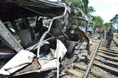 A solider walks near the remains of a bus after an intercity passenger train collided with it at a railway crossing at Polgahawela, a small suburb town about 80 kilometers (50 miles) northeast of Colombo, Sri Lanka, Wednesday, April 27, 2005.