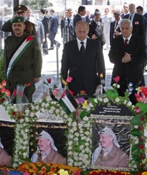Russian President Vladimir Putin, center, stands alongside Palestinian Authority President Mahmoud Abbas, also known as Abu Mazen, right, as he pays his respects at the grave of late Palestinian leader Yasser Arafat in the Palestinian Authority headquarters, in the West Bank town of Ramallah Friday, April 29, 2005. (AP