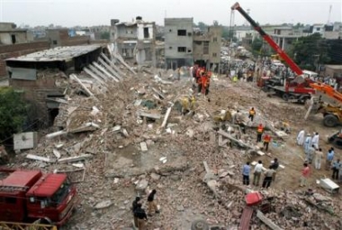 Pakistani rescue workers search the dead bodies at the site of a collapsed three story building in Lahore, Pakistan on Tuesday, May 3, 2005. Twelve people were killed and several others wounded when gas cylinders stored in basement of a building exploded in eastern Pakistan, causing the structure to collapse, police said. (AP