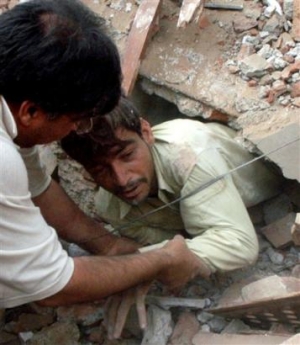 A wounded survivor is taken from the wreckage of three-story building, which collapsed, Tuesday, May 3, 2005. in Lahore, Pakistan Twelve people were killed and several others wounded when gas cylinders stored in basement of a building exploded in eastern Pakistan, causing the structure to collapse, police said. (AP