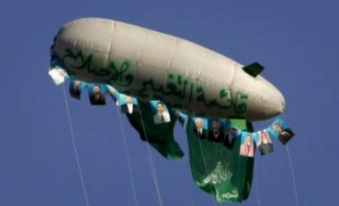 Hamas flags and pictures of Palestinian candidates from the Islamic resistance movement Hamas fly in the sky during a rally two days before the Palestinian local election at the Rafah refugee camp, southern Gaza Strip May 3, 2005. Palestinian police, enforcing a ceasefire with Israel, arrested two men from a suspected Hamas rocket squad after a gun battle in the Gaza Strip but freed the militants soon after, officials said on Tuesday. REUTERS