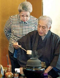 Chinese Vice-Premier Wu Yi looks over the shoulder of former Urasenke grand tea master Sen Genshitsu as he demonstrates a Japanese tea ceremony at a hotel in Nagoya, central Japan May 18, 2005. Wu is in Japan for a week-long visit and will meet Japanese Prime Minister Junichiro Koizumi as both sides seek to improve relations troubled by a series of feuds including Chinese anger at Koizumi's visits to Yasukuni Shrine, where convicted war criminals are honoured along with Japan's 2.5 million war dead.