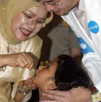 Mufidah Jusuf Kalla (L), the wife of Indonesia's Vice President Jusuf Kalla, gives a child a polio vaccine in Jakarta May 30, 2005. Indonesia will begin vaccinating more than six million children on Tuesday to try to halt a polio outbreak that has crippled 16 infants and toddlers in the country's first cases of the disease in a decade. REUTERS