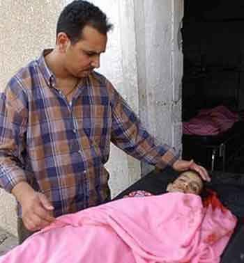 Majid Salih touches the face of his eleven-year-old niece Sabaa Haitham, in front of a morgue in Baghdad, Wednesday June 1, 2005. Sabaa, two other children and her uncle, were killed when a mortar shell landed outside their home in Baghdad's al-Doura neighborhood. (AP 