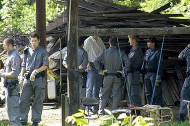 Austrian police stand in a shed near a house in the city of Graz, southeastern Austria, June 3, 2005. The bodies of four babies have been found at a house in Austria -- two in a freezer, one in a bucket of concrete and another in a nearby shed -- police said on Friday. REUTERS/