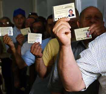 Lebanese Christian voters hold up their election identity cards at a polling station in the suburbs of Beirut June 12, 2005. Voters flocked to polling stations in central and eastern Lebanon on Sunday, where anti-Syrian factions squared off against each other in the most crucial round of the country's parliamentary elections. [Reuters]