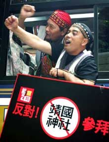 A group of Taiwanese indigenous people raise their fists and hold a banner protesting against the Yasukuni Shrine in Tokyo June 14, 2005. Prime Minister Junichiro Koizumi's visits to the Shinto Yasukuni shrine, where war criminals convicted by an Allied tribunal are honoured along with Japan's 2.5 million war dead, has been at the heart of diplomatic rows with China and South Korea and domestic pressure is mounting on him to stop going. A group of about 60 aborigines from Taiwan were prevented by Japanese police from approaching the shrine, where some two dozen members of Japanese right-wing groups faced off with around 10 police outside the massive 'torii' archway at the entrance.