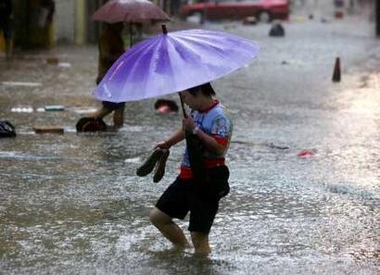 A woman wades through flood waters during heavy rains in downtown Hong Kong June 24, 2005.