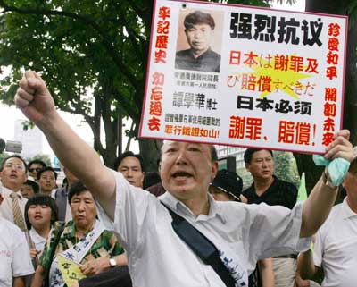 Tan Jialin of China holds up a sign with his father's portrait and a demand for an apology and compensation written in Japanese and Chinese during a protest, after a legal judgement, in front of the Tokyo High Court July 19, 2005. A Tokyo court on Tuesday rejected demands from Chinese plaintiffs for compensation and an apology from Japan's government for biological warfare conducted in China before and during World War Two. 