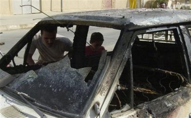 Iraqis inspect a burned vehicle after a car bomb, Monday afternoon, July 18, 2005, in Rawah, northwest of Baghdad, Iraq. A car bomb targeting Iraqi and U.S. troops exploded in Rawah, Monday , killing at least one person, witnesses said. (AP