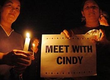 Nara Takakawa, left, and Sharon Reilly, right, hold candles and a sign with a message to President Bush, during a silent candlelight vigil in support of Cindy Sheehan, the mother of soldier Casey Sheehan. The vigil took place in Honolulu, Hawaii, Wednesday, August 17, 2005. [AP Photo]