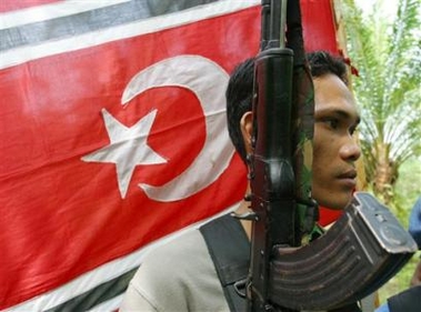 A rebel troop stands guard near the Free Aceh Movement flag during a press conference in Peureulak, Aceh province, Indonesia, Thursday, Aug. 18, 2005.
