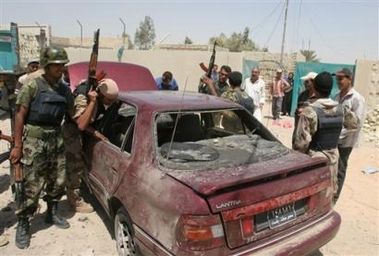 Iraqi soldiers inspect a car damaged from a road-side bomb attack, Thursday, Aug. 18, 2005, in eastern Baghdad, Iraq.