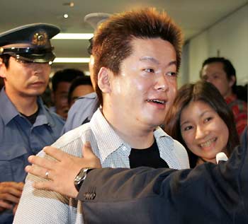 Maverick Japanese Internet CEO Takafumi Horie is guided past reporters after speaking at Japanese Prime Minister Junichiro Koizumi's Liberal Democratic Party headquarters in Tokyo August 19, 2005. The founder of high-flying Internet firm Livedoor Co will run as a de facto candidate for the LDP in next month's election in an attempt to topple an anti-reform rebel and woo undecided voters. [Reuters]