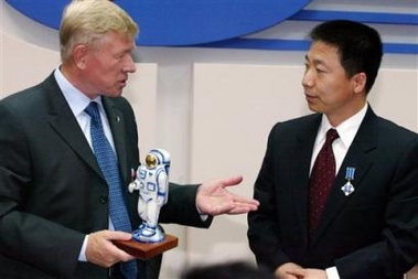 The head of Russia's space agency Anatoly Perminov, left, hands over a souvenir, a statuette wearing a space suit, to China's first man in space, Col. Yang Liwei shortly after he was presented with Russia's space agency award named after Soviet cosmonaut Yuri Gagarin, the first man in space, seen on Liwei's jacket, during their meeting in Moscow, Friday, Aug. 19, 2005. China's first man in space met with Russian space officials on Friday, discussed cooperation between the two countries and said he would enjoy flying aboard a new spacecraft Russia is designing. (AP