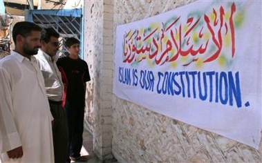 Iraqis look at the banner reading 'Islam is our constitution' in english and arabic, in predominately Sunni city of Ramadi, 113 kilometers (75 miles) west of Baghdad, Sunday, Aug. 21, 2005. Sunni Arabs warned they will reject the new constitution if Shiites and Kurds push it through parliament without Sunni consent. (AP 