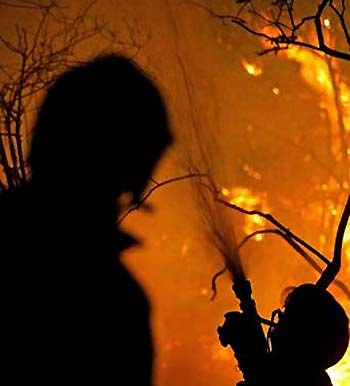 Two firefighters try to put out a forest fire in the outskirts of Viana do Castelo city in northern Portugal August 22, 2005. France, Germany, Italy and Spain offered Portugal help to battle forest fires raging across the country on Sunday after Lisbon made a request to the EU's executive Commission, officials and local media said. REUTERS