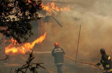 Firefighters work on a burning house in the village of Almalagues, near Coimbra, 200 kilometers (120 miles) north of Lisbon, Monday, Aug. 22, 2005