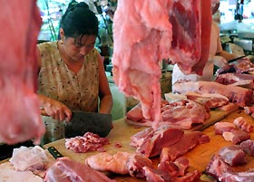 A vendor prepares pork at a market in Shanghai yesterday. Chinas far south is on high alert since one person was killed and three infected by a pig-borne disease that had left nearly 40 dead in the southwest. The latest person killed by the disease, caused by the Streptococcus suis bacterium, had handled infected pork, Xinhua news agency said on Tuesday. The three other victims, all butchers, also likely had contact with infected meat. 