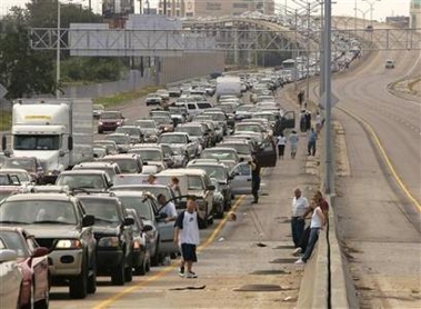 Drivers and passengers wait outside their cars as traffic snarls on the interstate highway leaving downtown New Orleans August 28, 2005. Authorities in New Orleans ordered hundreds of thousands of residents to flee on Sunday as Hurricane Katrina strengthened into a rare top-ranked storm and barreled towards the vulnerable U.S. Gulf Coast city. 
