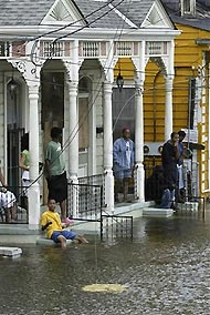 A family sits on their porch in the Treme area of New Orleans, which lies under several feet of water after Hurricane Katrina hit August 29, 2005.