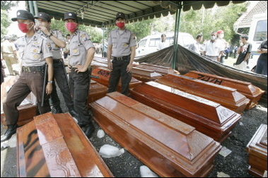 Indonesian poilcemen stand next to coffins containing the remains of unidentified victims of the crashed airliner in Medan, North Sumatra. 