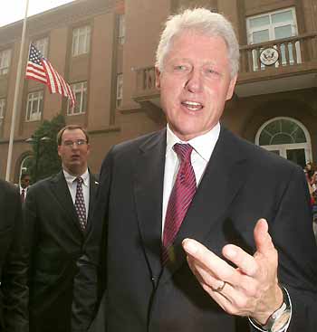 Former U.S. president Bill Clinton talks to the media near a U.S. flag raised to half mast during a service commemorating the September 11, 2001 attacks, at the U.S. embassy in Beijing September 11, 2005. [Reuters]