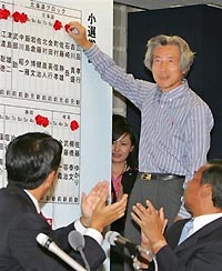 Prime Minister Junichiro Koizumi, top, leader of the Liberal Democratic Party (LDP), places a red rosette on a victorious candidate's name as the party's acting Secretary General Shinzo Abe, left, and the party senior leader Toshihiro Nikai clap hands during the ballot counting for the parliamentary elections at the party headquarters in Tokyo Sunday, Sept 11, 2005. 