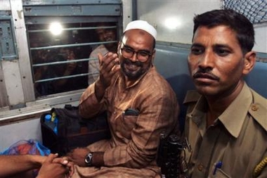 Pakistan national Mohammed Babbar, center, gestures to the photographer as he prepares to leave by train from New Delhi, India, Sunday, Sept. 11, 2005. Babbar had spent 15 years in Indian prisons after he had crossed the border from Pakistan. Ahead of the scheduled release Monday of 152 prisoners, who have served their sentence, many of them were released from various Indian jails and were being taken to the Wagah border in Punjab, where they would be handed over to the Pakistani authorities, according the news agency reports. At right is an Indian police officer. (AP