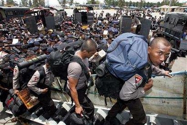 Members of the elite police mobile brigade carry their belongings as they board a naval vesel to leave Aceh in Lhokseumawe port September 14, 2005. More than 1,000 Indonesian police boarded a naval vessel to leave Aceh on Wednesday as part of a peace deal with rebels that will halve the number of security forces in the province. 