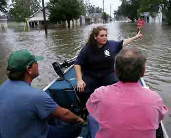 Resident Michelle Thibeaux (C) directs volunteers Tim Stelly (L) and Jay Roy Bernard (R) aboard a boat to her home in a neighborhood flooded by overflowing waters of the Vermillion River in the aftermath of Hurricane Rita in Erath, Louisiana September 24, 2005. [Reuters]