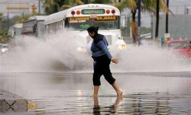 A woman walks on a flooded street at the Veracruz port in Mexico October 4, 2005.