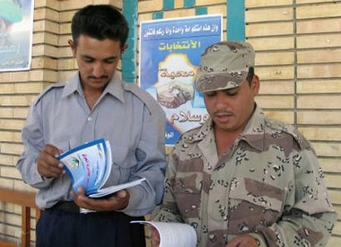 An Iraqi policeman and soldier read copies of Iraq's draft constitution in the town of Kut, 160 kms south of Baghdad October 8, 2005.