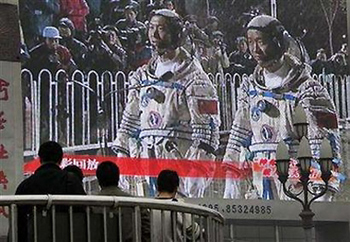 People watch a giant TV screen, showing astronauts Fei Junlong (L) and Nie Haisheng walking to the launch tower of the Jiuquan Satellite Launch Center in northwest China's Gansu Province, at Beijing's railway station October 12, 2005. Nie Haisheng turned 41 on Thursday. [Reuters]