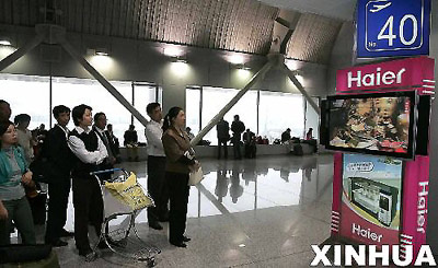Passengers watch the TV live broadcast of Shenzhou-6's lauch at Beijing International Airport on the morning of Oct 12, 2005. China's second manned spacecraft, Shenzhou-6, carrying two astronauts, successfully entered its planned orbit 21 minutes after lefting land on Wednesday morning, Oct 12, 2005.[Xinhua]