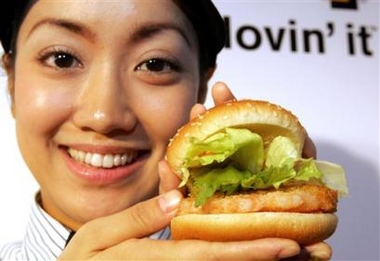 McDonald's Holdings Co. Japan Ltd. sales crew Kana Hattori shows off the humberger chain's new addition, shrimp burger, as it is unveiled to the media in Tokyo Friday, Oct. 14, 2005. Struggling to boost profits amid a price plunge for eating out, the shrimp burger is to keep a turnaround going, and is testing other new products, including yogurt and chicken salads. (AP Photo/Koji Sasahara) 