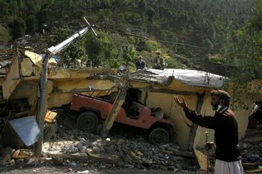 Pakistani earthquake survivors sit on the roof of their destroyed home in Balakot, Pakistan Sunday, Oct. 16, 2005.