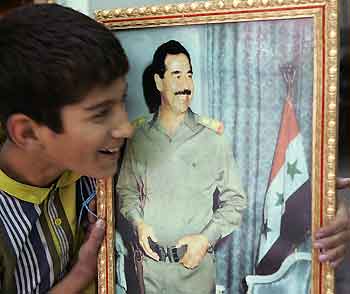 A young Jordanian holds up a poster of former Iraqi President Saddam Hussein for sale in downtown Amman October 19, 2005.
