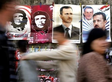 Syrians walks infront of posters showing President Bashar Assad and Cuban revolutionary leader Ernesto 'Che' Guevara , left, in Damascus, Syria, Wednesday Oct.26, 2005.