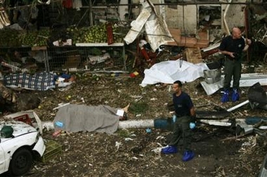 Covered bodies lie on the ground as Israeli policemen inspect the area of a suicide bomb attack in the Israeli coastal city of Hadera, some 40 km (25 miles) north of Tel Aviv, Wednesday Oct. 26, 2005.