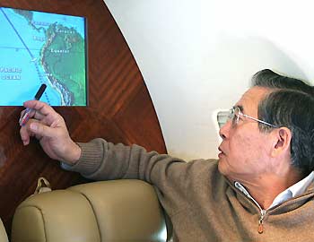 Former Peruvian President Alberto Fujimori looks at an in-flight video showing the route of his flight from Tokyo to Santiago de Chile, November 6, 2005.
