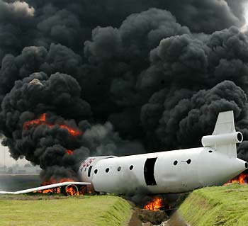 A column of smoke rises from a mock passenger plane during a crash rescue exercise at the tarmac of the Manila International airport November 9, 2005. The exercise tests the preparedness of firefighters, medical personnel and the police in case of an actual crash at the airport.