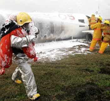 Filipino firefighters douse chemicals on a mock plane during a crash rescue exercise at the tarmac of the Manila International airport November 9, 2005.