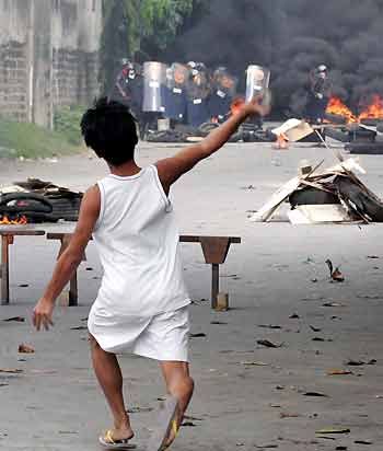 A Filipino protestor throws a rock during a clash with Special Weapons and Tactics (SWAT) members of the Philippine National Police and members of a demolition team during a demolition at St. Joseph compound in Sun Valley, Paranaque city, south of Manila November 14, 2005.