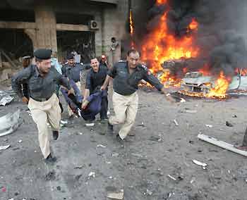 Pakistani police officials carry a body from a building after a bomb blast in Karachi November 15, 2005.