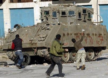 Palestinians hurl stones at an Israeli army vehicle during clashes in the West Bank town of Jenin, Wednesday Nov. 23, 2005.