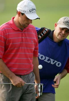 Oliver Wilson of England (L) tosses the ball beside his caddie after putting at the 12th green during the third round of the $1.2 million China Open golf tournament at Shenzhen Golf Club, China's southern city of Shenzhen, November 26, 2005.