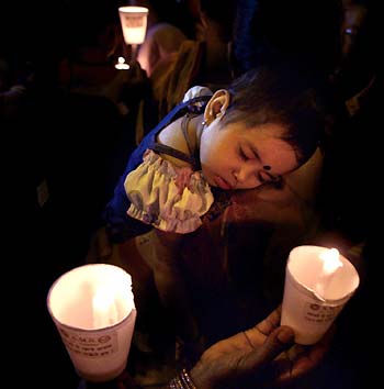 The daughter of a commercial sex worker sleeps as her mother holds a candle during an AIDS awareness rally in Mumbai, India November 29, 2005. The rally ended with sex workers making a pledge to protect themselves from getting AIDS and also to help in the treatment and respect people who are suffering from AIDS.